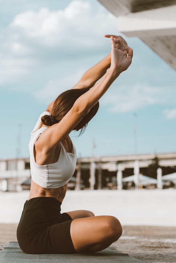 Woman performing yoga stretches outdoors on a mat, embracing an active lifestyle.